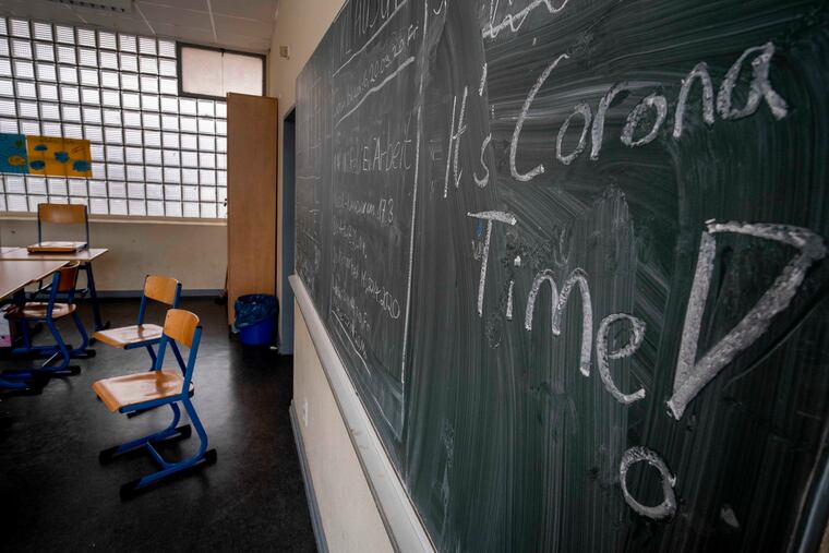 In this Friday, March 13, 2020 photo, a slogan on a chalkboard reads 'It's Corona Time' in an empty class room of a high school in Frankfurt, Germany. In the U.S. employers must pay an employee's compensation if they miss work because they need to care for a child whose school is closed due to COVID-19. (AP Photo/Michael Probst, file)