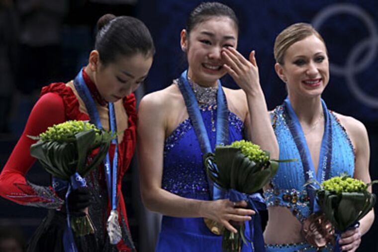 Gold medallist Kim Yu-Na of South Korea, center, reacts as she stands on the podium with silver medallist Mao Asada of Japan, left, and bronze medallist Joannie Rochette of Canada, right, during the medal ceremony for the women's figure skating competition. (AP Photo/Mark Baker)