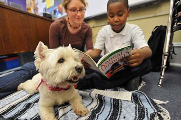 Lacey and owner Sarah Brenner of Wayne listen to Christian Hankerson, 8, read a book as part of the Wag Tales program at Gesu School. (Sharon Gekoski-Kimmel / Staff Photographer)