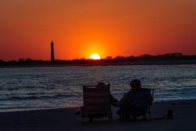 A couple watches a sunset at the Jersey Shore. Come Sunday, the sun won't be setting until after 7.