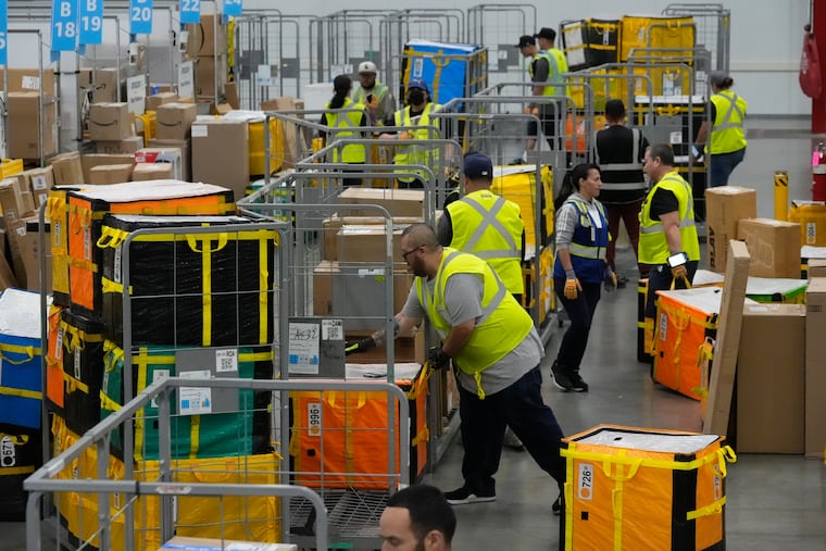 FILE - Amazon employees load packages on carts before being put on to trucks for distribution to customers for Amazon's annual Prime Day event at an Amazon's DAX7 delivery station on July 16, 2024, in South Gate, Calif. (AP Photo/Richard Vogel, File)