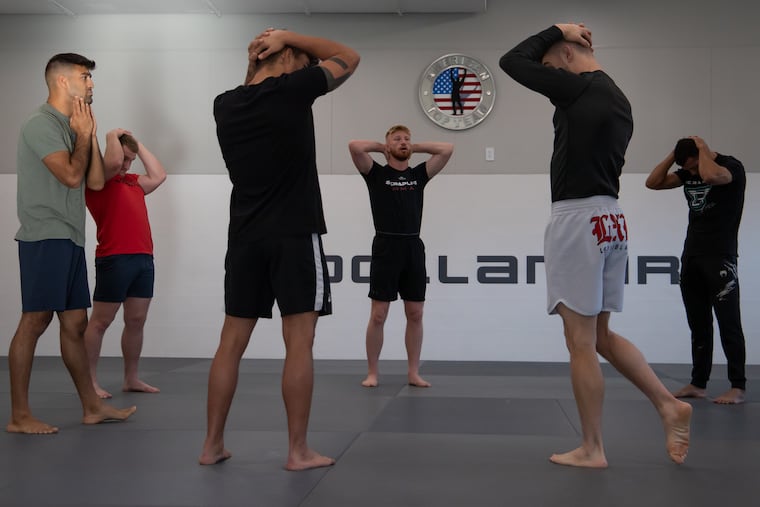 Alongside other athletes and coaches, Bo Nickal stretches before a morning training session at American Top Team Happy Valley in Pleasant Gap, Pa.