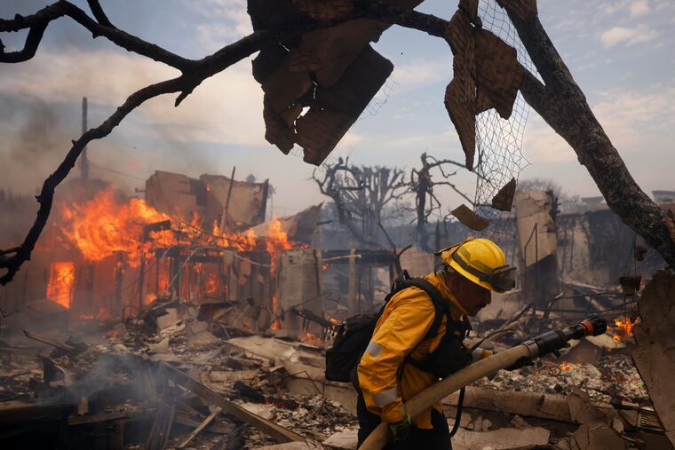 A firefighter battles fire around a burned structure in the Pacific Palisades neighborhood of Los Angeles on Wednesday.