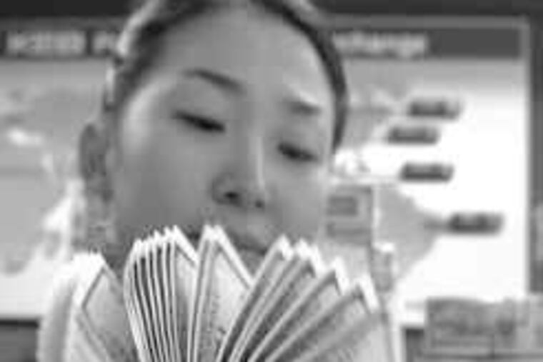 A Korea Exchange Bank clerk checks U.S. $100 bills at the bank's headquarters in Seoul, South Korea. The dollar replaced the British pound as the world's currency around World War II.