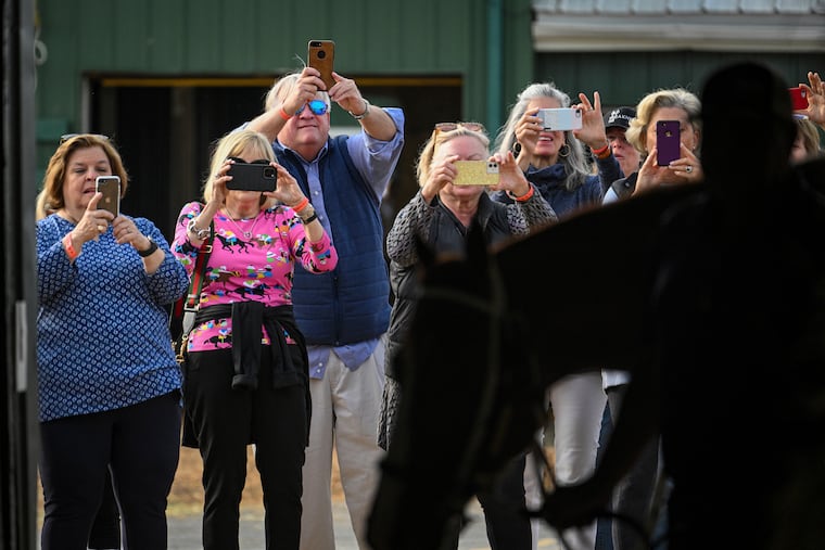Fans on a tour of Pimlico take photos of Kentucky Derby winner Mage as he is walked around the Stakes Barn before a workout Tuesday in preparation for Saturday's Preakness Stakes.