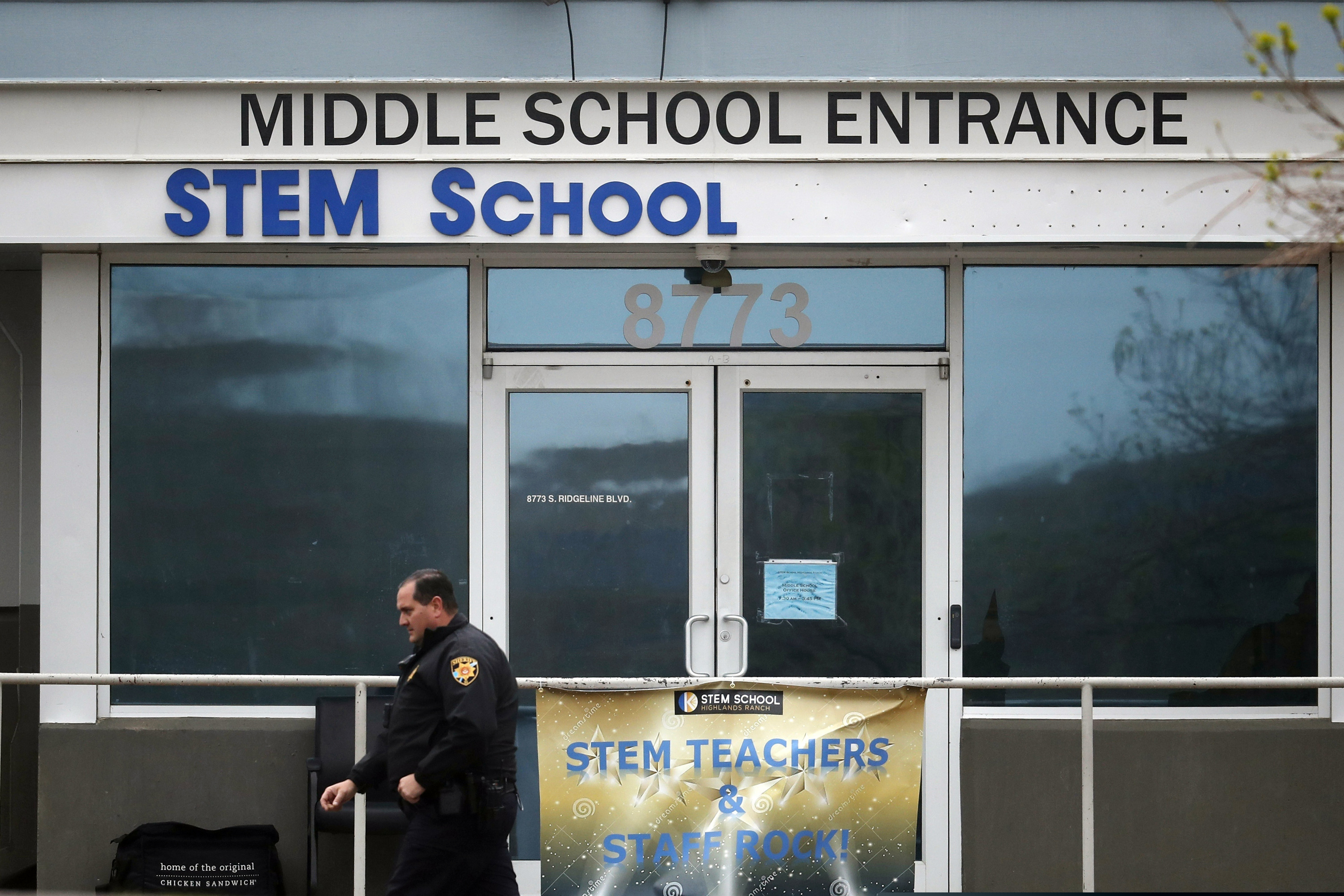 FILE - In this Wednesday, May 8, 2019, file photo, a Douglas County, Colo., Sheriff's Department deputy walks past the doors to the STEM School Highlands Ranch, in Highlands Ranch, Colo. A high school student charged in a classmate’s death during a shooting at the school told police that he planned the shooting for a few weeks and intended to target classmates who made fun of his gender identity.