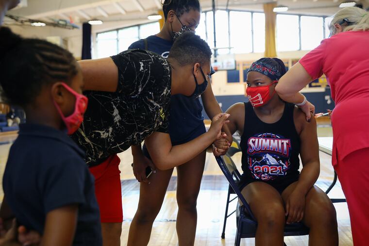 Nurse Kimball Dunlap (right) administers the first dose of the Pfizer COVID-19 vaccine to Jazmyne Collins (second from right)at Cheltenham High School in May.