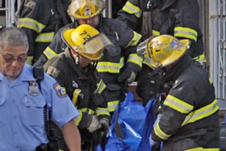 Firefighters remove the body of the fire victim from the house on Luray Street in the Feltonville section of Philadelphia.