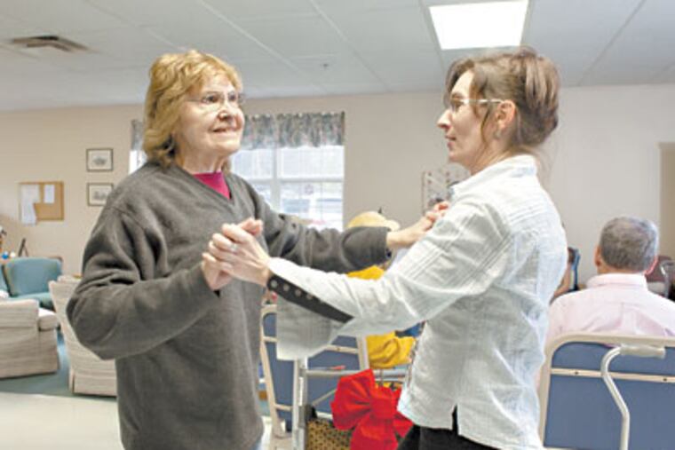 Nela Baker (left) who is dealing with frontotemporal dementia, dances with team leader Claudia Sequeira during exercise at Adult Care of Chester County. (ED HILLE / Staff Photographer)