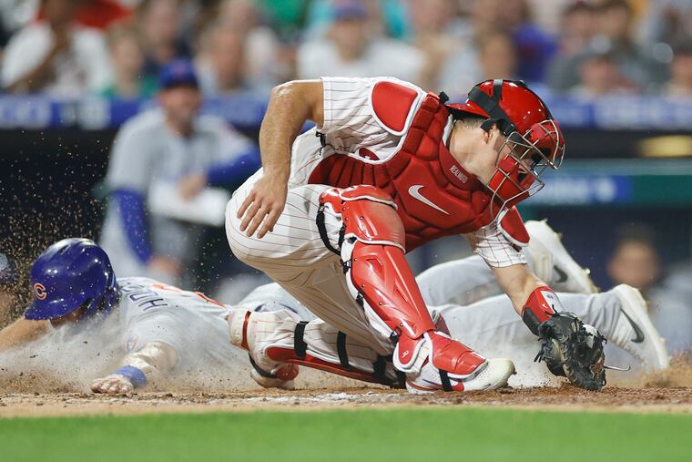 Nico Hoerner slides home past Phillies catcher J.T. Realmuto in the top of the 10th inning on Saturday.