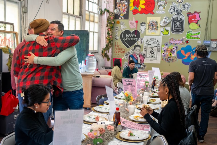 Sean Skulski (left) and Mannie Aguirre greet each other among fellow diners at a free breakfast at the floral studio of Caitlyn Augustyn in Kensington on Sunday morning, Nov. 9, 2025.