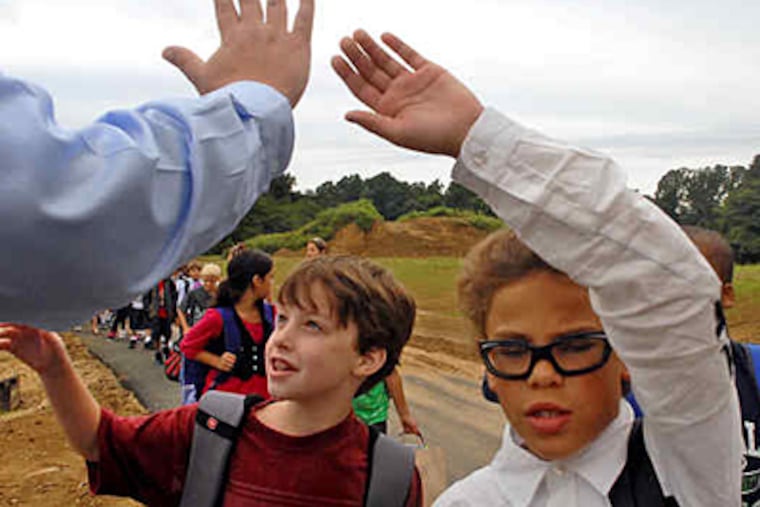 On opening day at the new Rainbow Elementary School in the Coatesville district , third graders Dalton Valentine (left) and Stefon Tracey give high-fives to music teacher Tom Hartwell. The district is building and renovating as it emerges from years of turmoil. (Tom Gralish / Staff)