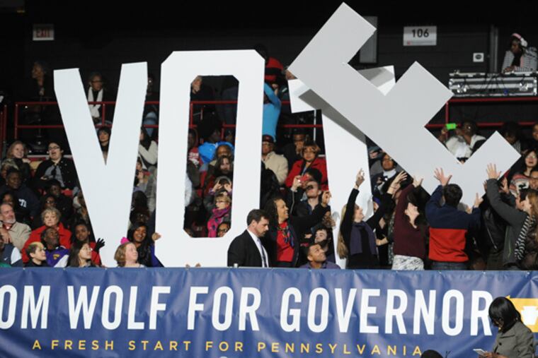 Getting the letters in place encouraging people to vote at a campaign rally for Tom Wolf, Democratic candidate for governor of Pennsylvania, at Temple University in which President Obama appeared and gave remarks Nov. 2, 2014. (CLEM MURRAY/Staff Photographer)