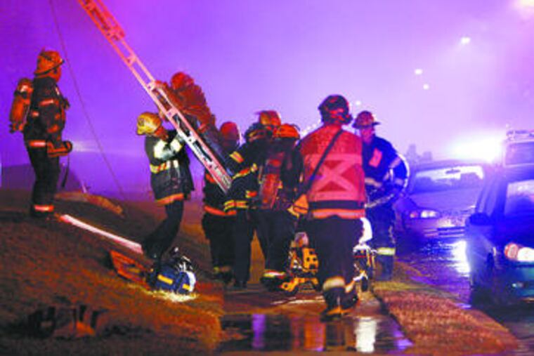 Firefighters extend a ladder to rescue a resident from the four-alarm fire at the Bradford Arms apartments.
