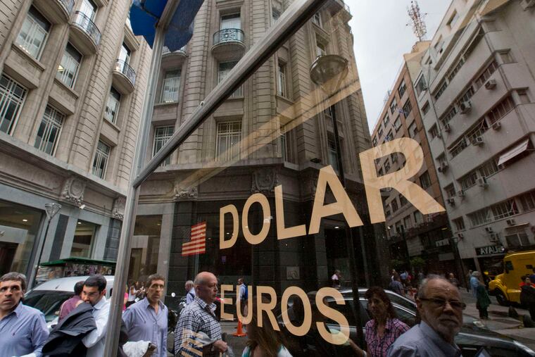 People in Buenos Aires walking outside a money-exchange house Thursday, the first day of Argentina's free-floating peso. President Mauricio Macri lifted currency controls to fulfill campaign pledges to kick-start the economy by enacting free-market policies. Argentina's finance minister declared opening day a success, saying the peso's decline - 27 percent against the dollar - was in line with his expectations. "We're very calm," he said.