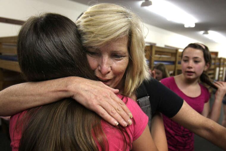 Lori Murphy gets a hug from daughter Mackenzie as they check in at Camp Mariposa in Quakertown. In the background is her other daughter, Maddy.
