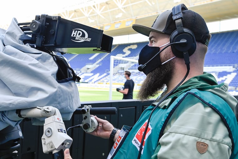A tv cameraman wears a face mask as he stands on his position in the stadium prior to the Bundesliga soccer match between TSG 1899 Hoffenheim and Hertha Berlin in Sinsheim, Germany.