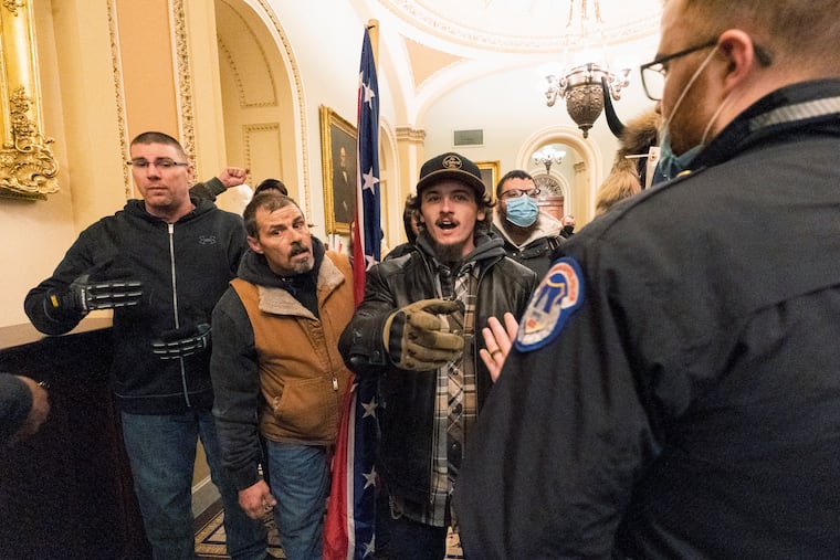 Kevin Seefried, second from left, holds a Confederate battle flag as he and other insurrectionists loyal to President Donald Trump are confronted by U.S. Capitol Police officers outside the Senate Chamber inside the Capitol in Washington on Jan. 6, 2021.