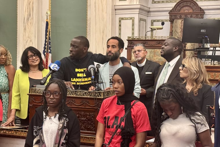 City Councilmember Isaiah Thomas (center, black t-shirt) puts his arm around Jonathan Hoffmeier, a teacher at Lankenau High School, one of the 17 schools the Philadelphia school board has said it will close. Thomas and other Council members are attempting to get the board to negotiate on school closings; the board has declined.