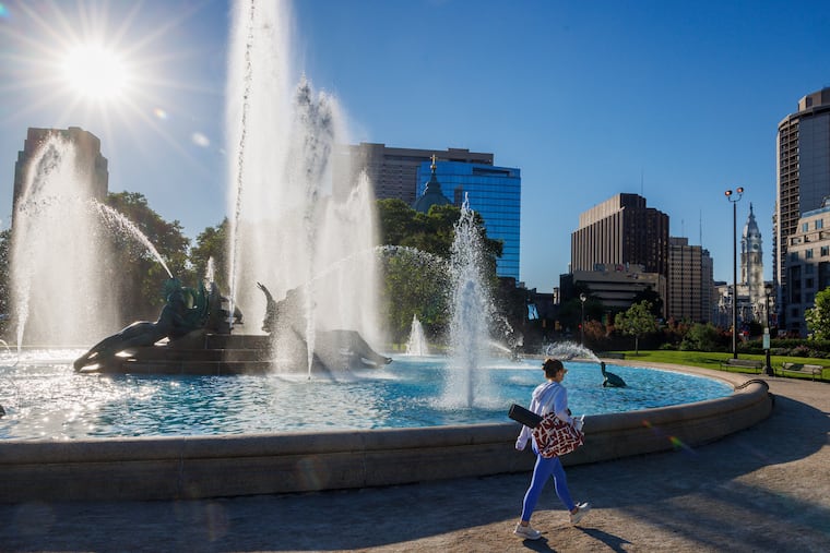 A woman walks past Swann Memorial Fountain as the sun starts to rise last month. The region has had more than its share of early heat.