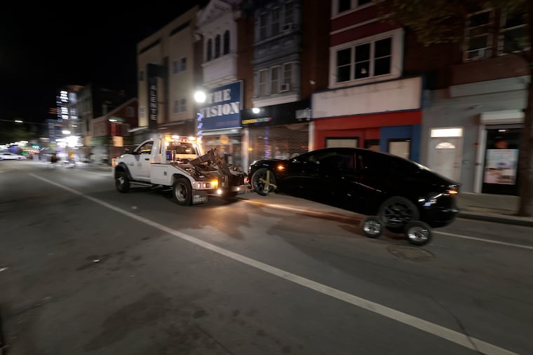 A Philadelphia Parking Authority tow truck tows a car off South Street in Philadelphia in June.