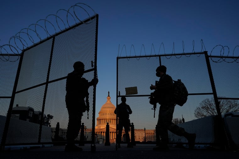 In this March 8 photo, members of the National Guard opened a gate in the razor wire topped perimeter fence around the Capitol at sunrise.