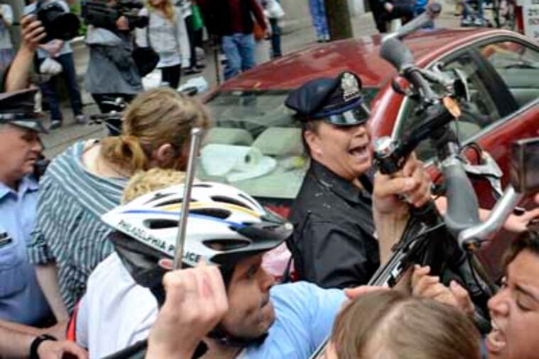 Police officers use their bicycles to keep Occupy Philadelphia members back as one is taken into custody. Occupy blocked the street outside a bank branch on Walnut Street as part of a May Day protest. TOM GRALISH / Staff Photographer