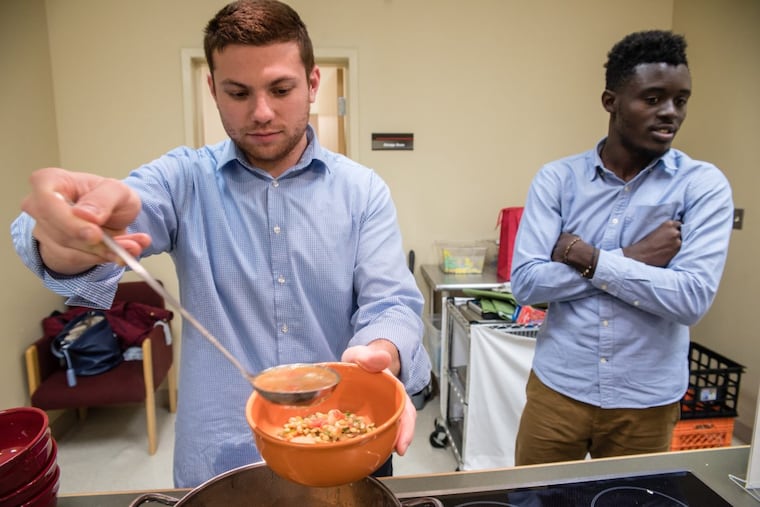 Temple medical student David Pioquinto ladels out a bowl of lentil soup he and classmates made in November 2016, during a healthy cooking class at the Lewis Katz School of Medicine. Hilario Yankey awaits his share.