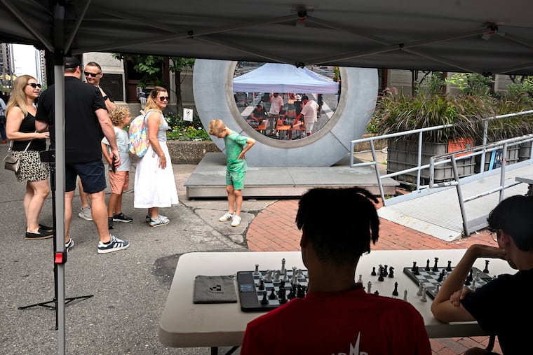 The Vlaming and Van Voorn familes stop to watch a chess match game at the portal in City Hall Sunday, as players in Dublin, Lublin, Philadelphia, and Vilnius play each other with portals in each city serving as a digital window, allowing players to see one another while they're playing. The Vlamings are visiting from Breda, in the Netherlands. Their friends, the Van Voorns, live in Wayne. Playing are Richard Robinson (left), 17, of Northeast Philadelphia, and Chris Romeril (right), 16, of Collegeville, with the Tri Bridges Chess Club of Exton.