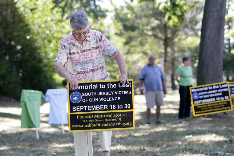 Carol Suplee of Lumberton installs a sign commemorating the victims on the grounds of the meetinghouse in Medford. The display on Union Street will be the first in South Jersey and will remain at that location for two weeks.