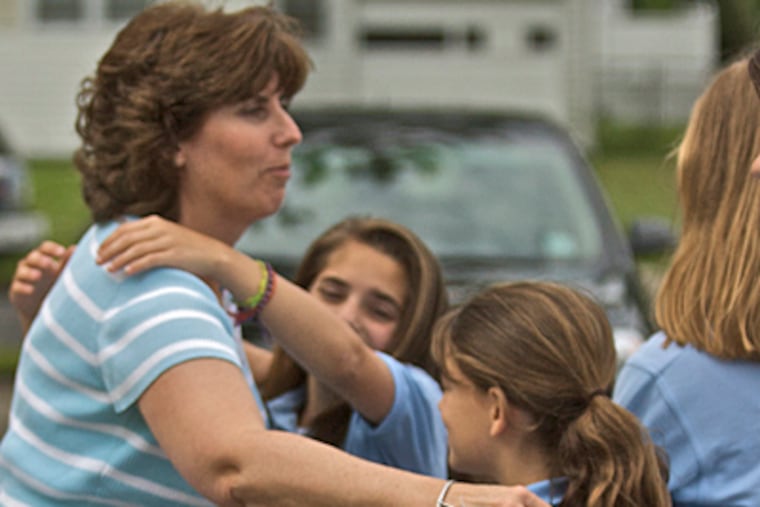 Denise Lundholm, a mother of a student, a former student herself and a 5th-, 6th-, 7th- and 8th-grade math teacher at Sacred Heart hugs students goodbye. ( John Costello / Staff Photographer )