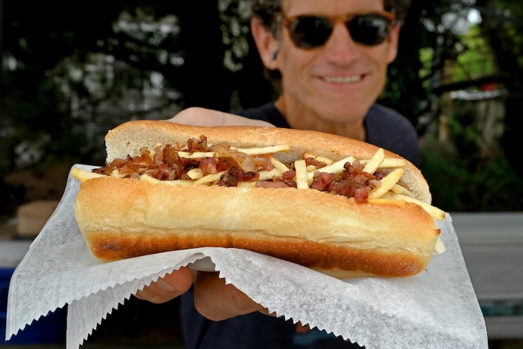 Tim McNamara serves up a 59th Street 100% all beef hot dog on a freshly baked bun with Cheese Whiz, bacon, BBQ sauce and crunchy potato sticks. "The dog that made us famous," at Bubba Dogs in Sea Isle City.