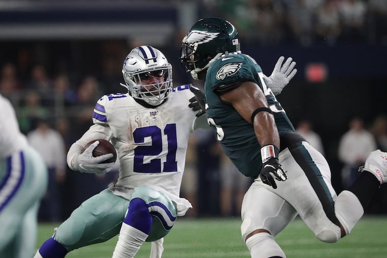 Dallas Cowboys running back Ezekiel Elliott (left) makes Eagles defensive end Brandon Graham miss a tackle during a run Sunday night.