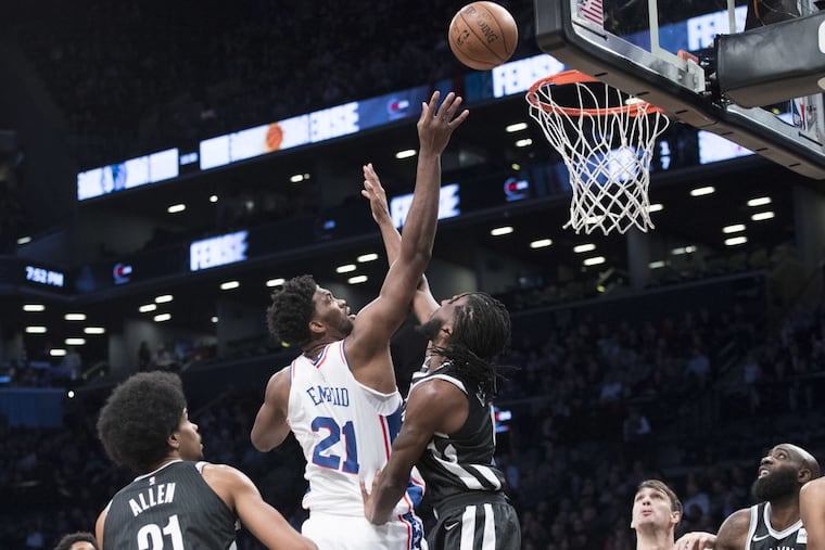 Philadelphia 76ers center Joel Embiid shoots over Nets big man Jarrett Allen (eft) and forward DeMarre Carroll during the first half of the Sixers’ loss.