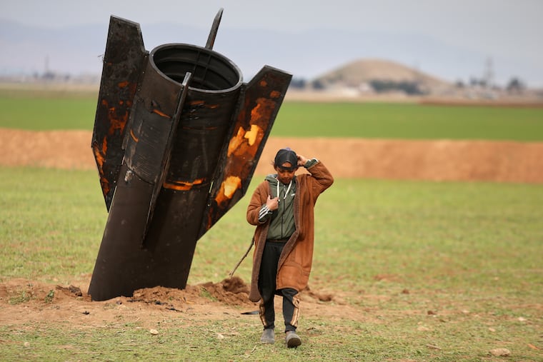 A shepherd boy walks away from an unexploded Iranian projectile that landed in an open field in the outskirts of Qamishli, eastern Syria, Wednesday, March 4, 2026.