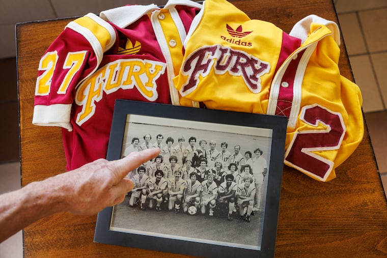 Kevin Murphy, who played for the Philadelphia Fury in the 1970s, points out a team photo along with a pair of old uniforms.