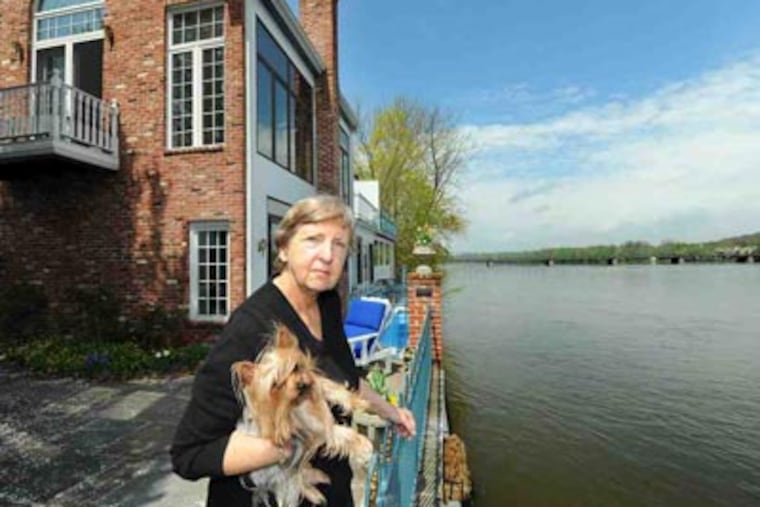 Gail Pedrick stands on the patio of her New Hope home overlooking the Delaware while holding Daisy, her Yorkie. She helped lead a petition drive on reservoir levels. (Clem Murray / Staff Photographer)