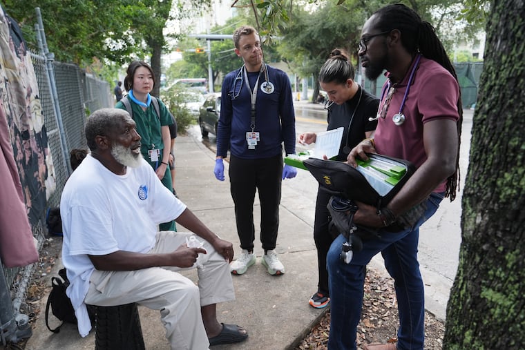Dr. Inaki Bent, right, talks with Jonas Richards, left, while working with the Miami Street Medicine team to provide medical services to homeless people, Saturday, Aug. 23, 2025, in Miami. (AP Photo/Lynne Sladky)