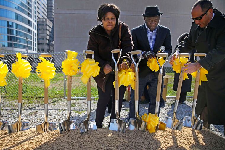 Kadie Conteh (left), Aiah Boya (center) tied yellow ribbons on the shovels used for a memorial at the Salvation Army site for victims of the building collapse. The trial is on hiatus until Nov. 15.