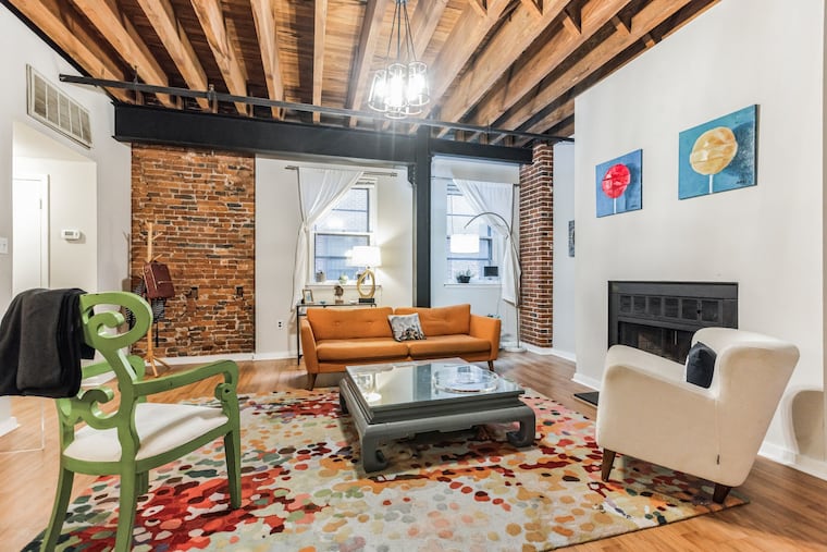 The living room of the Old City condo features exposed brick and beams.