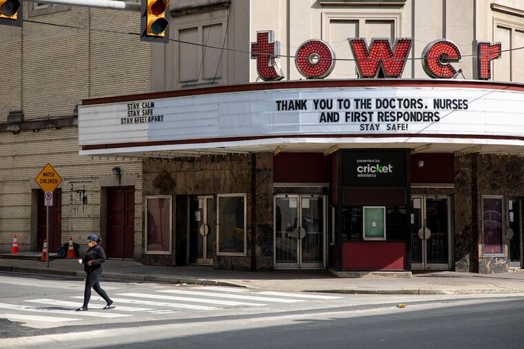 A woman wearing a protective mask walks by Tower Theater in Upper Darby on Saturday, the marquee bearing the message, "Thank you to the Doctors, Nurses, and First Responders. Stay Safe!” Health-care workers have become the nation's new superheroes as they staff the front lines against the coronavirus.