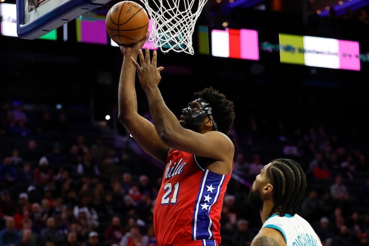 Sixers center Joel Embiid lays-up the basketball past Charlotte Hornets center Nick Richards in the first quarter Friday night.