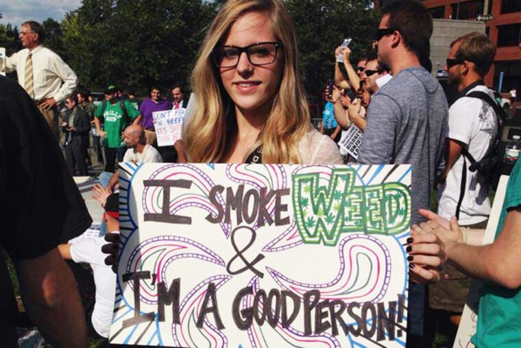 A PhillyNORML volunteer holds a sign at a Smoke Down Prohibition rally in Philadelphia's Independence National Historic Park