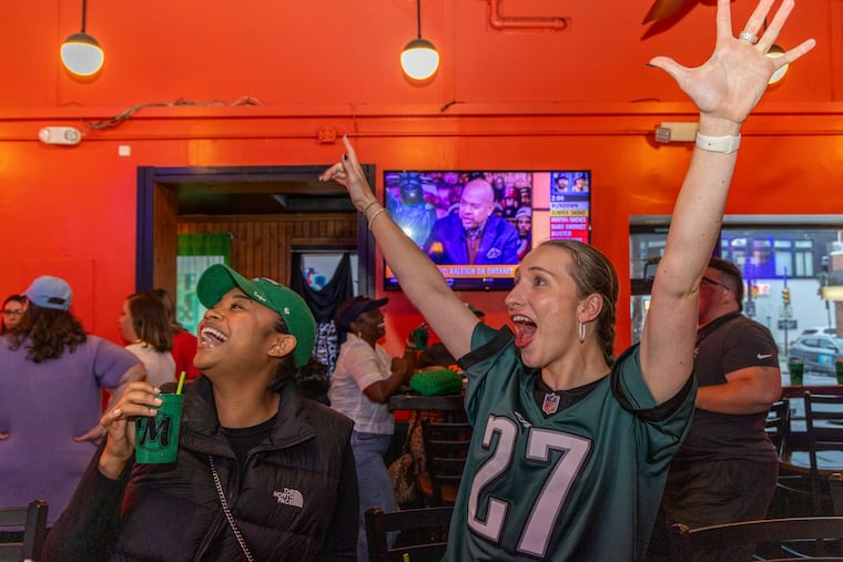 Dominique Johns (left) and Olivia Vance watch an Eagles game at Marsha’s on South Street last month. Tonight the Eagles, Phillies, and Flyers will all be playing.