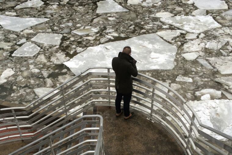 A pedestrian pauses to look at the ice build up along the Delaware River at Penn's Landing in Philadelphia, on Tuesday, March 3, 2015. Yet another round of winter weather in Pennsylvania has prompted flight cancellations and delays, speed reductions on highways and the Pennsylvania turnpike and early dismissal of some school classes — but officials are already focusing on a larger storm expected later in the week. (David Maialetti / Staff Photographer)