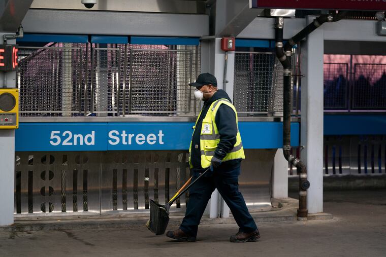 FILE- In this March 18, 2020 file photo, SEPTA worker Ervin Lavenhouse wears a mask as he works sweeping up trash on the platform at the 52nd Street station, in Philadelphia. The Transport Workers Union that represents nearly 5,000 employees of Philadelphia's regional mass transit authority wants the Southeastern Pennsylvania Transportation Authority to remove a cap on paid leave if workers are exposed to coronavirus.
