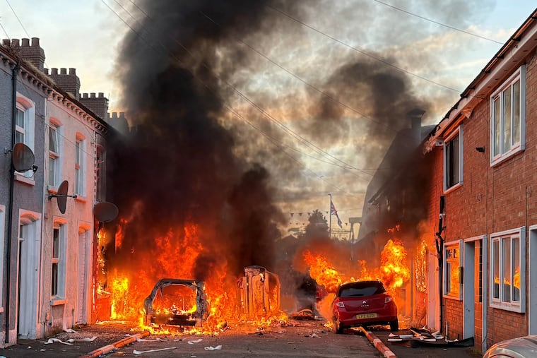 Vehicles set on fire by protesters burn on Lendrick Street in east Belfast, Northern Ireland, on Tuesday, after the arrest of a Sudanese man accused in a stabbing.