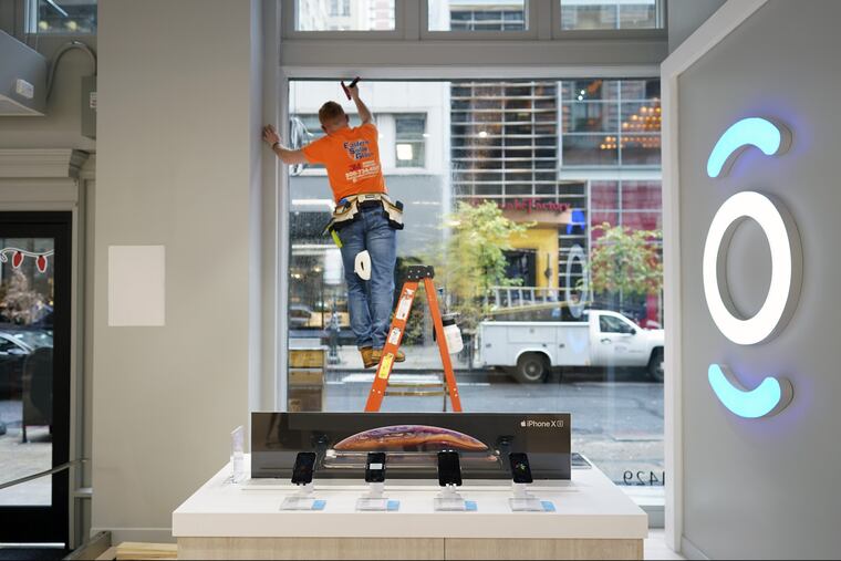 A worker washes the windows of the new Xfinity store on Walnut Street, which opens Thursday.