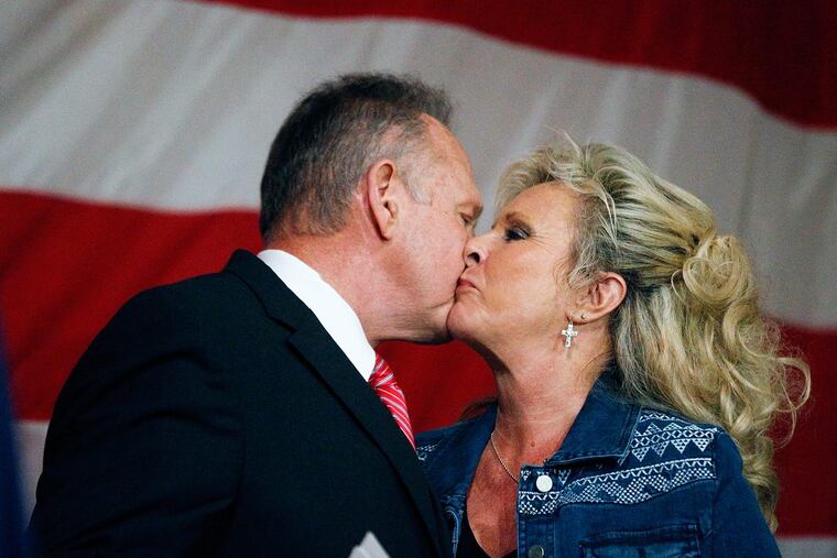 Former Alabama Chief Justice and U.S. Senate candidate Roy Moore kisses his wife, Kayla Moore, after speaking at a Dec. 5 campaign rally in Fairhope, Ala.