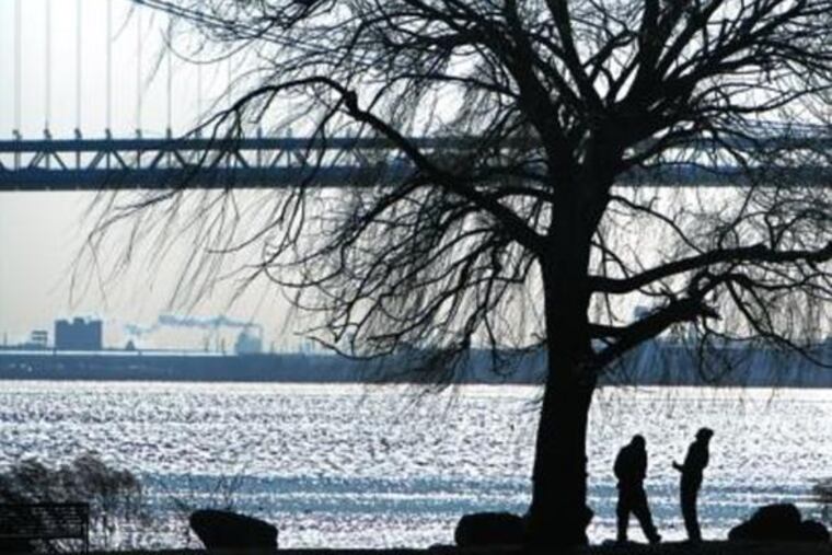 TWO MEN PAUSE under a bare tree in Penn Treaty Park along the bank of the Delaware River in the Fishtown section on Monday, a day the temperature didn't climb out of the 20s.